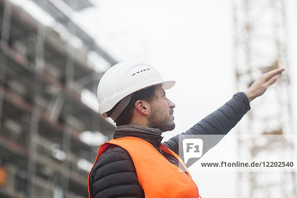 Man with wearing safety vest and hard hat at construction site