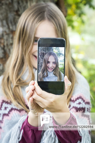 Portrait of laughing girl taking selfie with cell phone