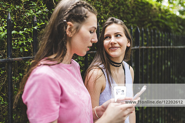 Two teenage girls with cell phone outdoors