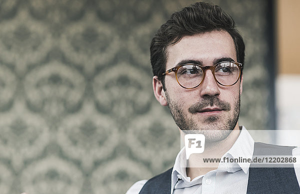 Porträt eines jungen Mannes mit Brille  der zur Seite schaut.