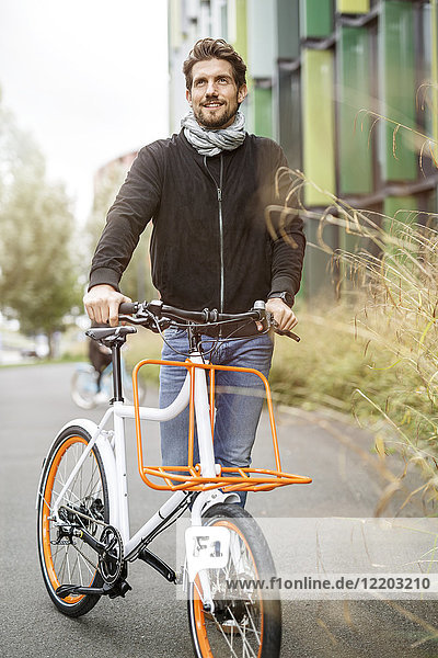 Smiling man with bicycle on a lane