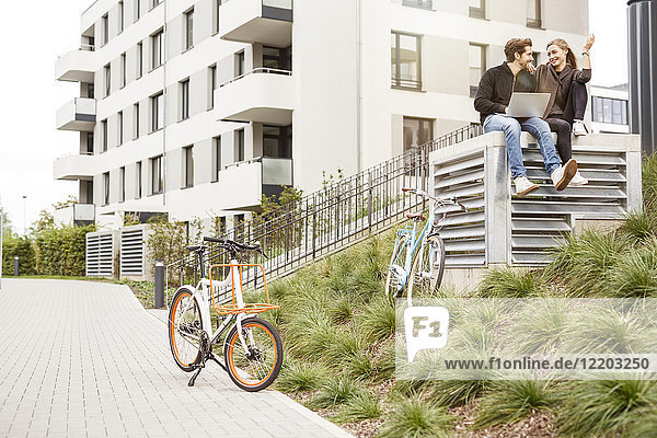 Glückliches Paar mit Fahrrädern und Laptop in urbaner Umgebung