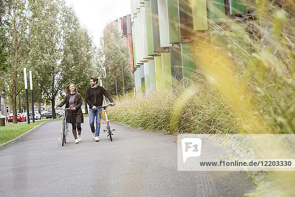 Smiling couple walking with bicycles on a lane