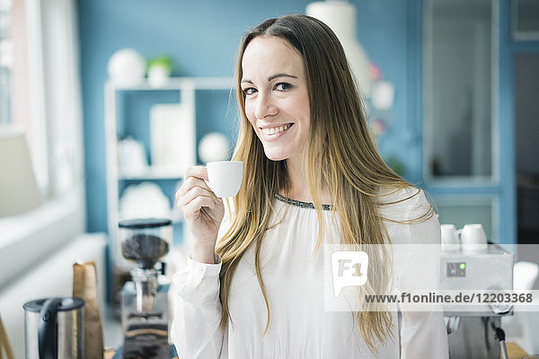 Porträt einer glücklichen Geschäftsfrau  die in der Küche eines Loftes Espresso trinkt.