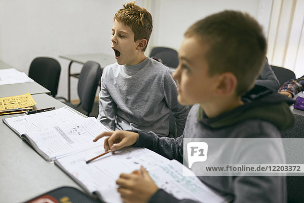 Students learning in class with boy yawning
