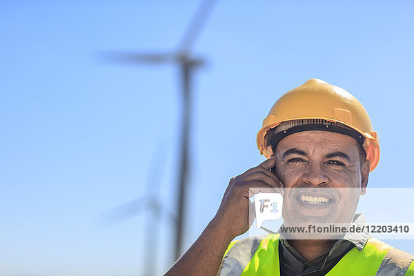 Portrait of smiling technician on cell phone on a wind farm