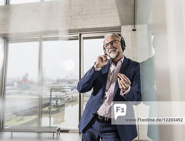 Passionate mature businessman listening to music on headphones