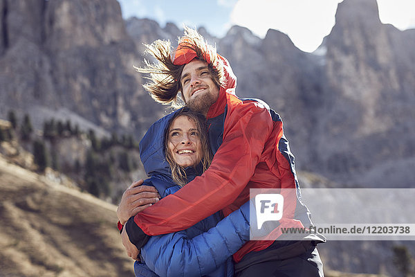 Happy young couple hugging in windy mountains