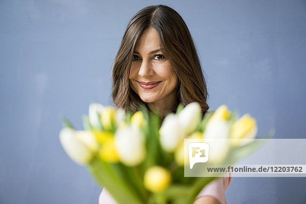 Porträt einer lächelnden Frau mit Tulpenstrauß