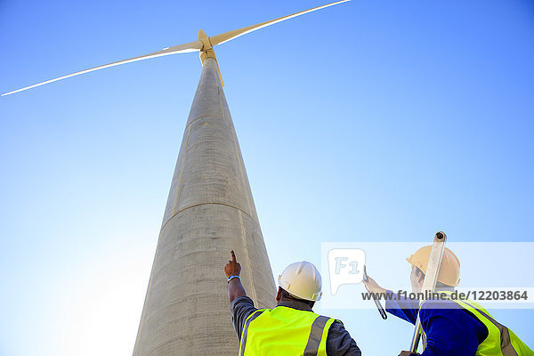 Low angle view of technicians in front of wind turbine