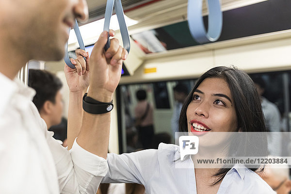 Geschäftsfrau im Gespräch mit Geschäftsmann in der U-Bahn