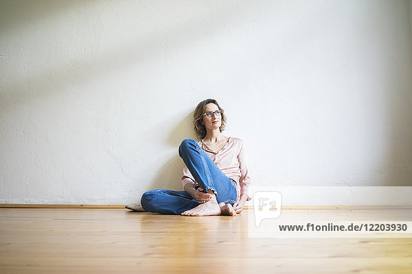 Mature woman sitting on floor in empty room thinking