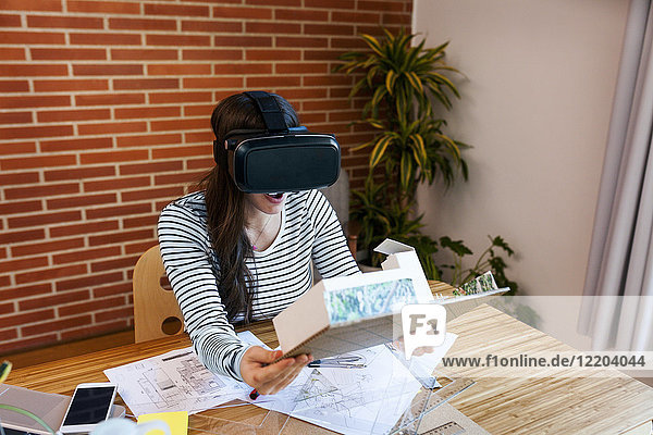 Young woman working in architecture office  looking at model with VR goggles