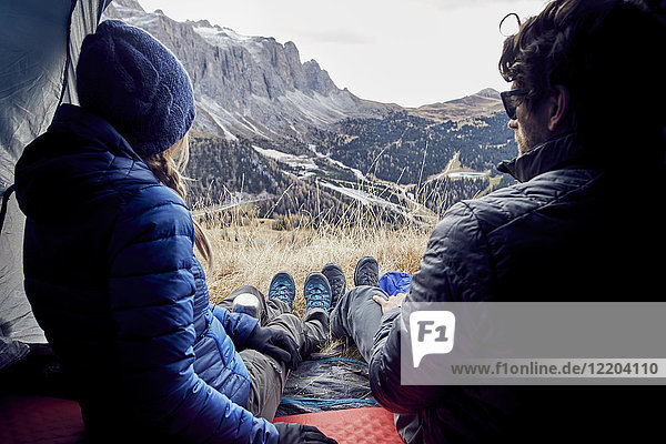 Couple sitting in tent in the mountains looking at view