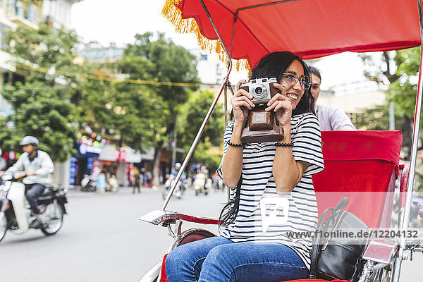 Vietnam  Hanoi  junge Frau mit altmodischer Kamera auf einer Riksha