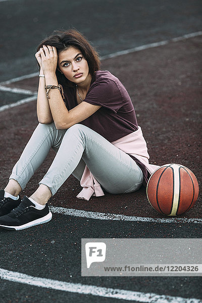Porträt einer jungen Frau mit Basketball auf dem Außenplatz