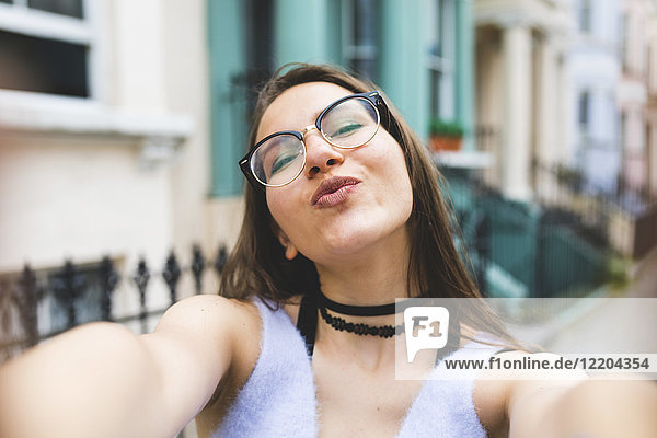 Fröhliches Teenagermädchen in der Stadt mit einem Selfie