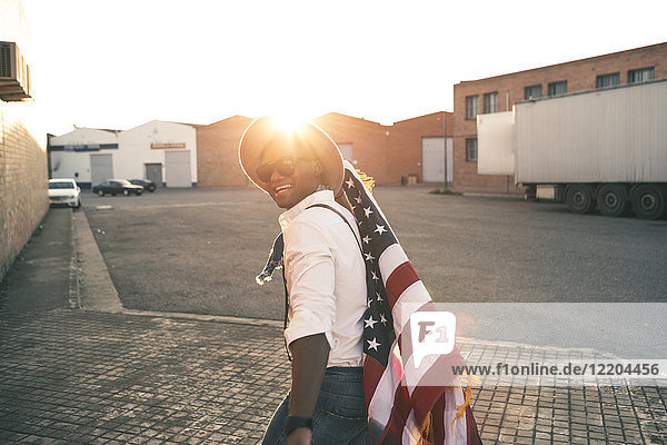 Laughing young man with American flag at backlight