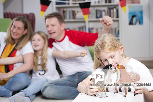 Family watching football world cup on TV  while little girl is playing with toys
