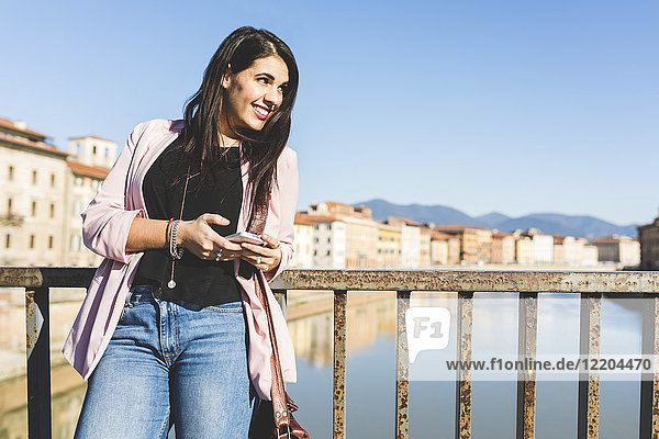 Young businesswoman with smartphone on a bridge in the city