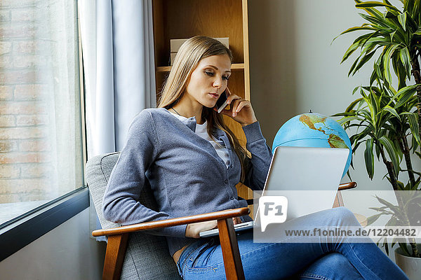 Junge Frau im Sessel sitzend mit Laptop