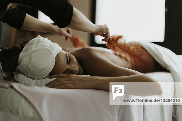 Junge Frau erhält eine Massage mit Federn in einem Spa