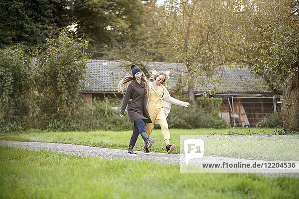 Zwei glückliche Frauen  die in der ländlichen Landschaft spazieren gehen.