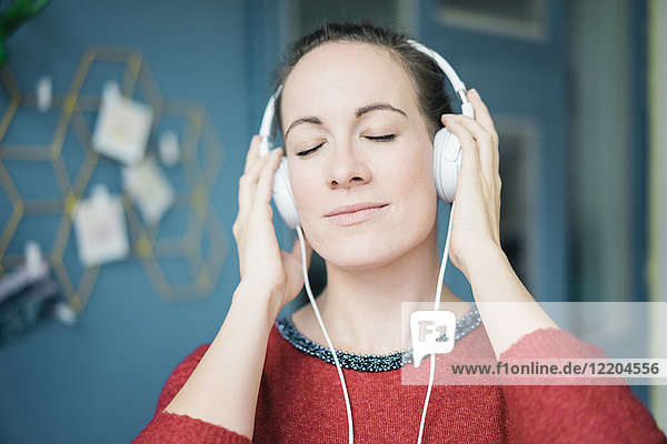 Porträt einer Frau mit geschlossenen Augen Musik hören mit Kopfhörer