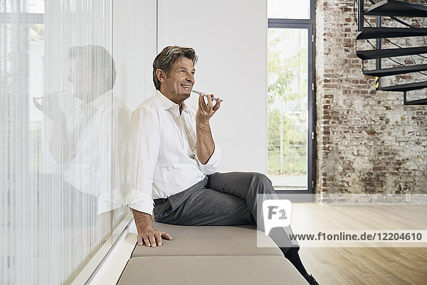 Geschäftsmann sitzt auf der Bank im modernen Büro mit Smartphone