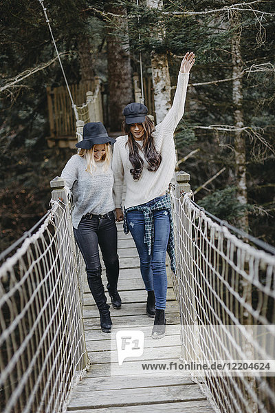 Zwei glückliche junge Frauen  die zusammen auf einer Aufhängung laufen.