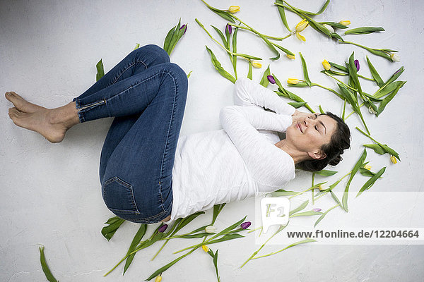 Lächelnde Frau inmitten von Tulpen auf dem Boden liegend