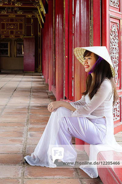Eine Frau in einem traditionellen Ao-Dai-Kleid und einem konischen Non-La-Hut in der Verbotenen Purpurnen Stadt Hue  UNESCO-Weltkulturerbe  Thua Thien Hue  Vietnam  Indochina  Südostasien  Asien