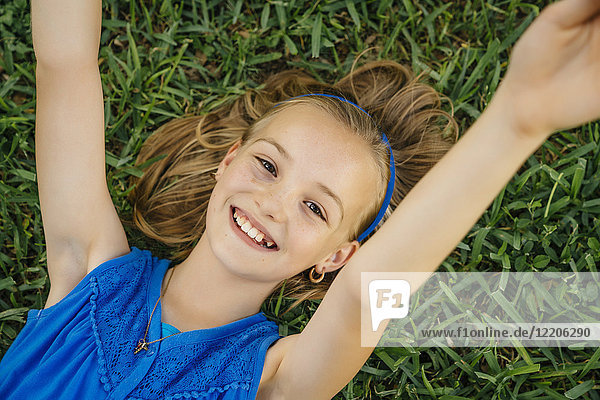 Close up portrait of smiling Caucasian girl laying on grass