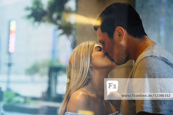 Caucasian couple kissing behind window