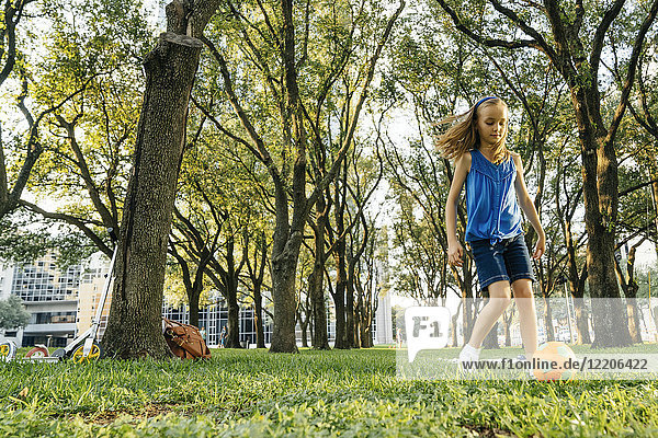 Kaukasisches Mädchen kickt Fußball im Park