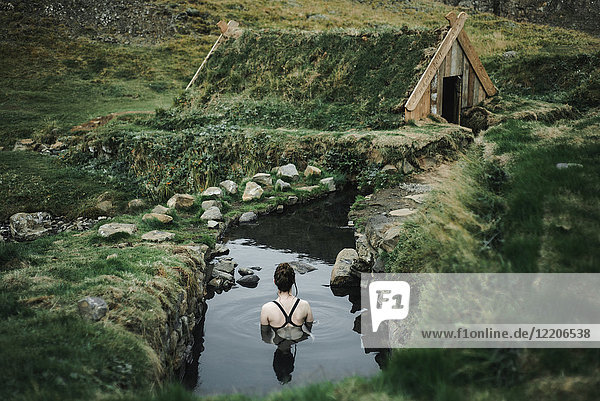 Kaukasische Frau schwimmt in einem Teich in der Nähe eines ländlichen Hauses