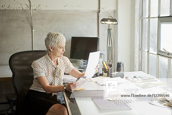 Kaukasische Geschäftsfrau liest Papierkram im Büro