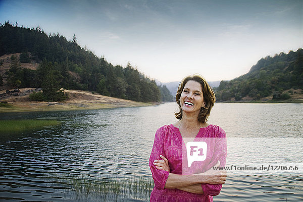 Smiling Hispanic man standing near lake