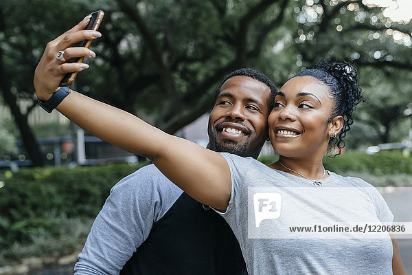 Smiling Black couple posing for cell phone selfie
