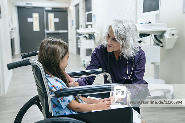 Smiling doctor talking to girl in wheelchair