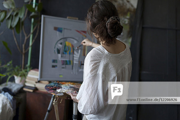 Rear view of Caucasian woman painting on easel