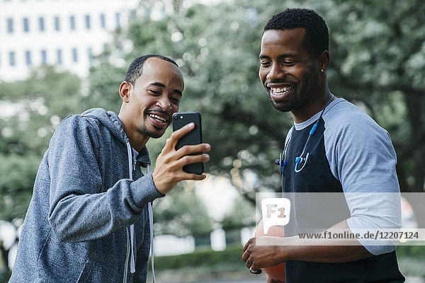 Smiling Black men texting on cell phone