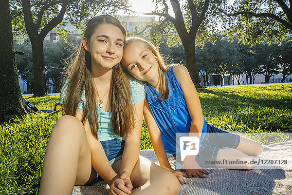Portrait of smiling Caucasian girls on blanket in park