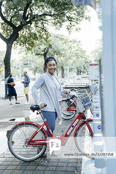 Black woman posing with rental bicycle