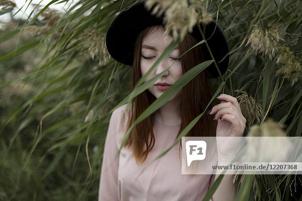 Pensive Asian woman standing in field of tall grass