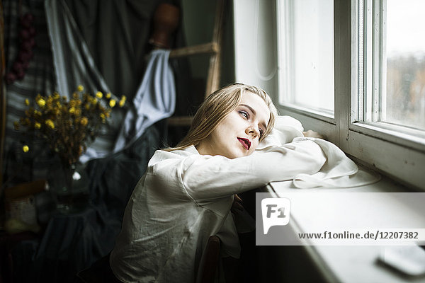 Portrait of pensive Caucasian woman leaning on window sill