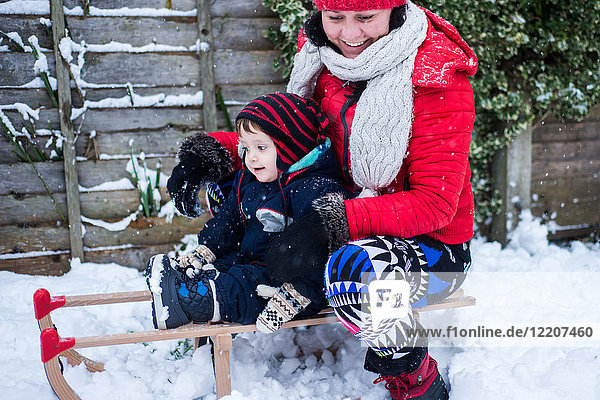 Mother and son in snow on toboggan