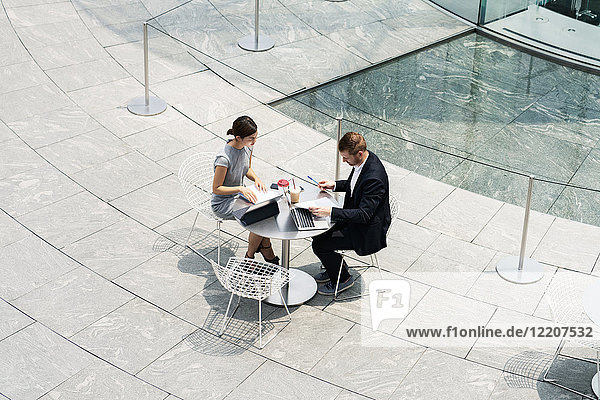 Young businesswoman and man meeting at sidewalk cafe  high angle view