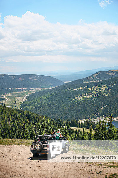 Road trip couple looking out at mountains from off road vehicle hood  Breckenridge  Colorado  USA