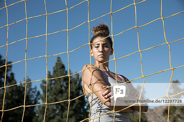 Porträt einer Frau hinter einem Fußballtornetz  die in die Kamera schaut
